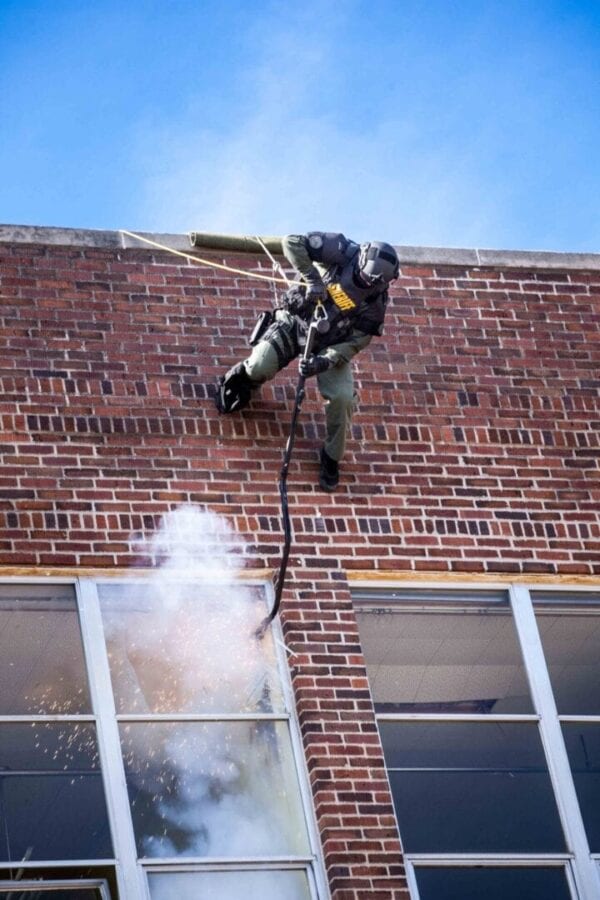 A firefighter is spraying a building with a fire extinguisher.