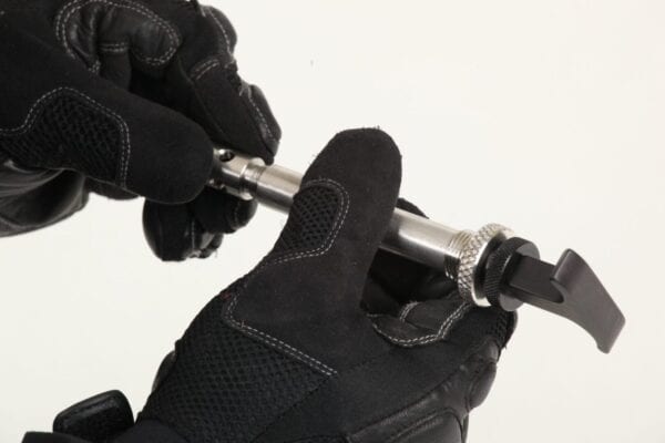A person wearing black gloves is holding a metal tool.