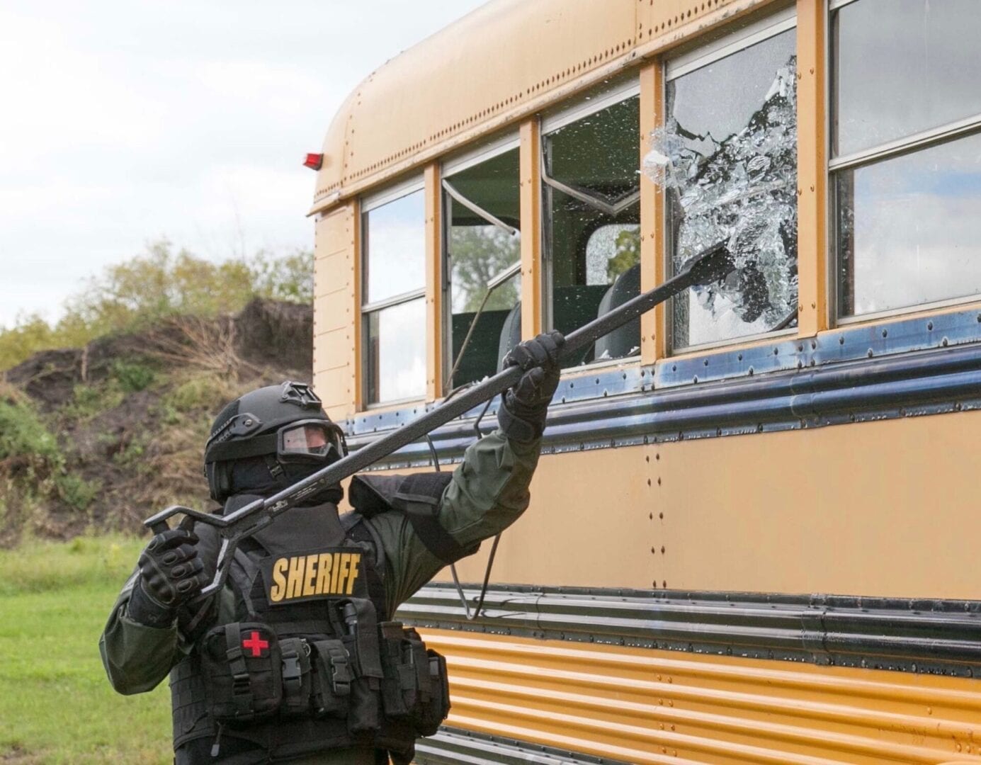 A police officer spraying a school bus with a hose.