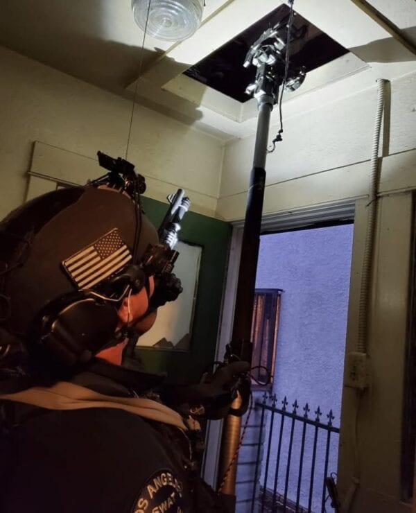 A police officer using a RDT - RECON SCOUT ROBOT DELIVERY TOOL on a ceiling.