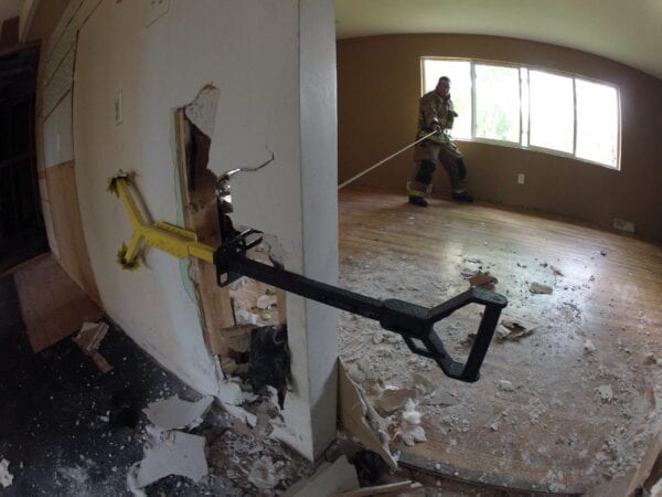 A firefighter uses a RIT-3 Tool in a damaged room.