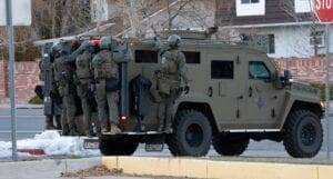 An armored vehicle is parked next to a stop sign.